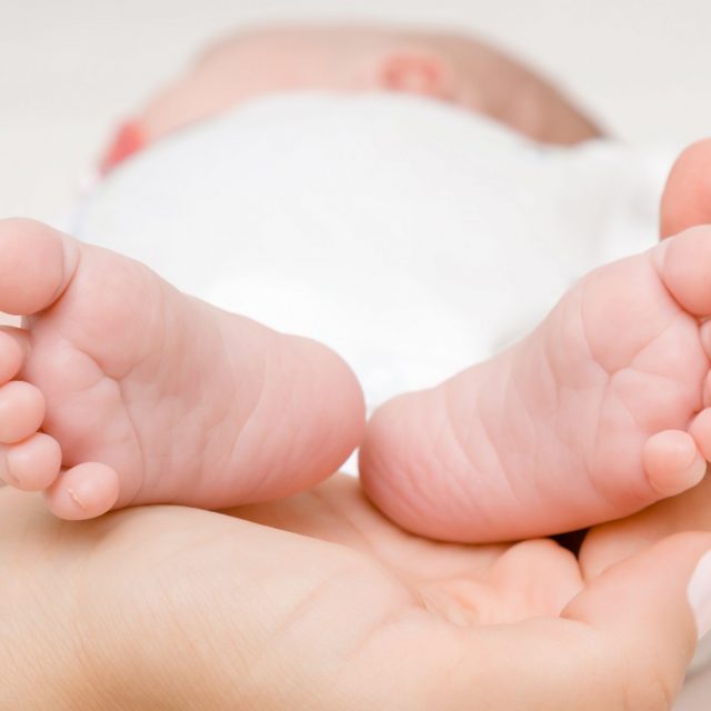 Newborn cute feet in young mother palm. Lovely, emotional moment. Closeup.