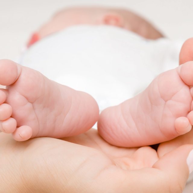 Newborn cute feet in young mother palm. Lovely, emotional moment. Closeup.